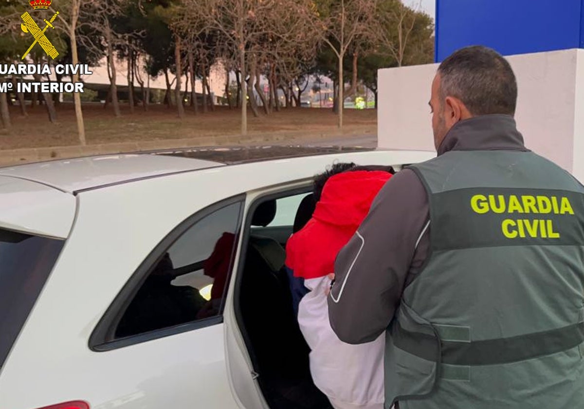 Un guardia civil introduce al detenido en un vehículo.