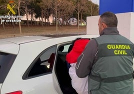 Un guardia civil introduce al detenido en un vehículo.