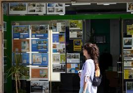 Una joven observa los anuncios de alquiler de una inmobiliaria en Valencia.