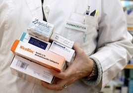 Una farmacéutica sostiene algunos medicamentos que ayudan a dejar de fumar.