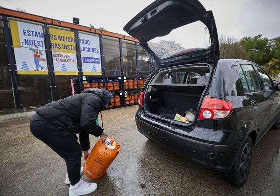 Un joven cargando una bombona de butano en su coche.