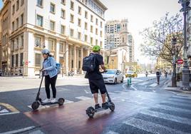 Varios usuarios circulan en Valencia en patinete eléctrico.