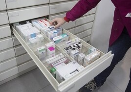 Un farmacéutico valenciano busca un medicamento en su establecimiento.