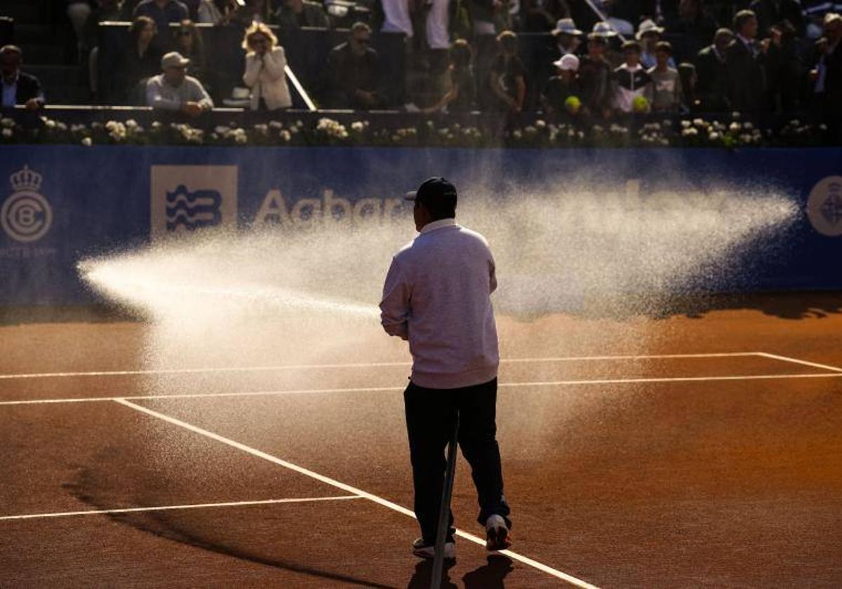 Un trabajador riega la pista Rafa Nadal en la jornada de este martes.