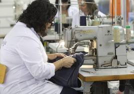 Una mujer cose unos vaqueros en Jeanología, una de las empresas textiles punteras en la Comunitat.