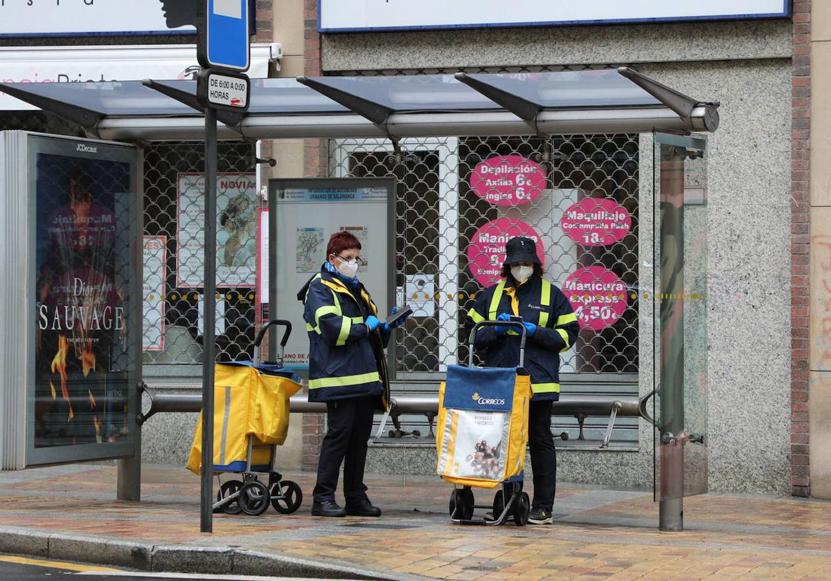 Dos carteras de Correos en una parada de autobús en una imagen de archivo