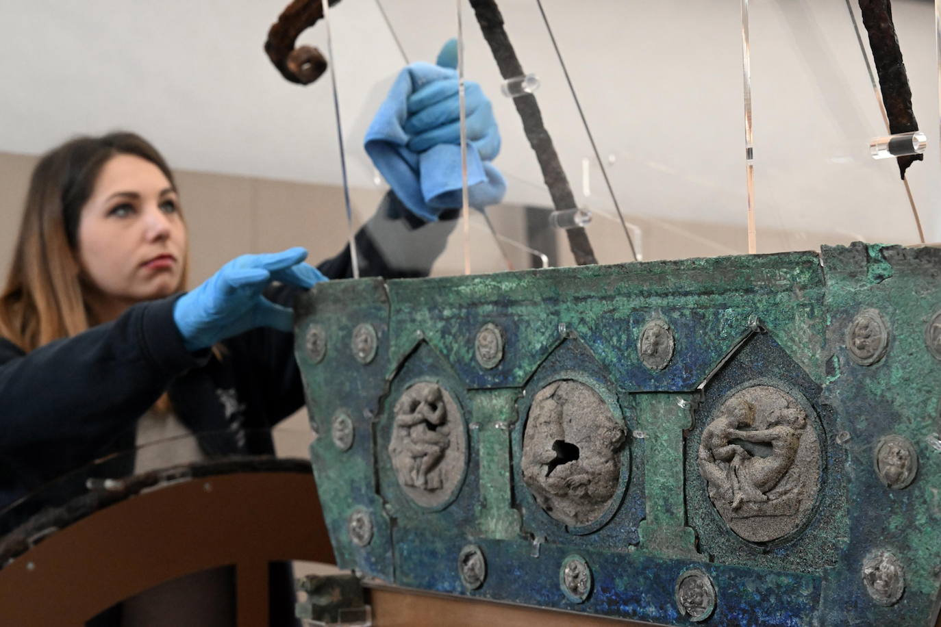 Una arqueóloga limpia una de las piezas de nueva factura antes de la exposición del carro.