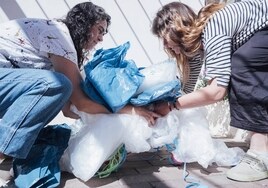 Dos mujeres recogen bolsas de plástico para realizar las tote bag.