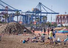 Turistas y valencianos, junto a las montañas de arena, en la playa del Cabanyal, junto a La Marina.