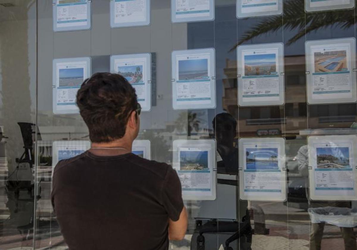 Un hombre observa información sobre propiedades en una inmobiliaria.