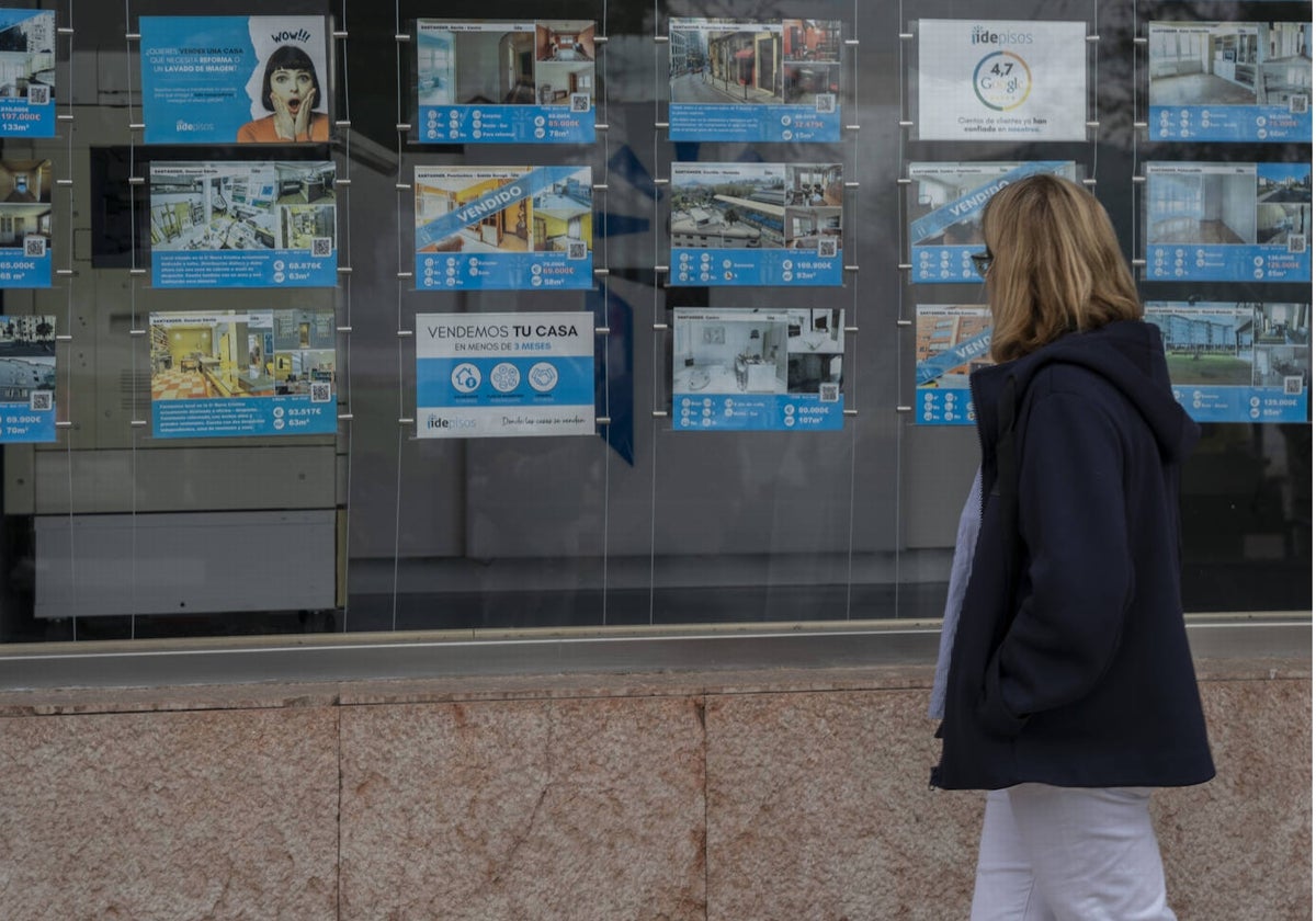 Una mujer observa el escaparate de una inmobiliaria.