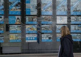 Una mujer observa el escaparate de una inmobiliaria.