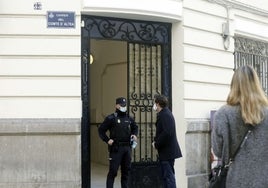 Un policía haba con un hombre en la puerta de la finca donde tuvo lugar el crimen.