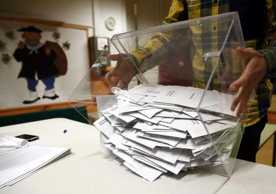 El presidente de una mesa electoral deposita los votos de la urna sobre una mesa para proceder a su recuento.