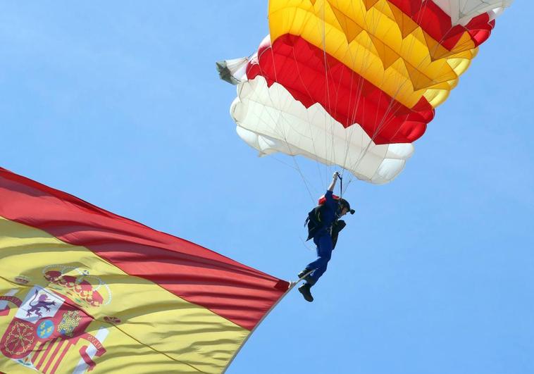 La cabo paracaidista Carmen Gómez Hurtado desciende con una bandera de España durante el desfile de las Fuerzas Armadas.