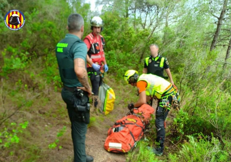 Dos bomberos, un guardia civil y un policía local junto a la víctima inmovilizada en la tabla de rescate.