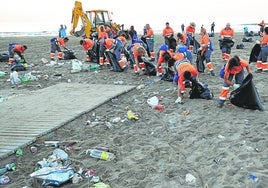 Los trabajadores de limpieza recogen la basura de la playa de la Malvarrosa después de San Juan.