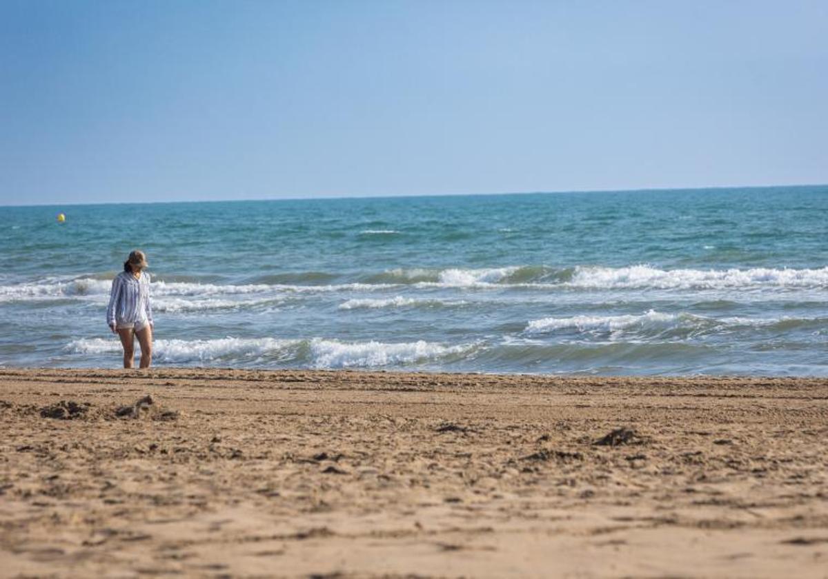 Una mujer pasea por una playa en Valencia.