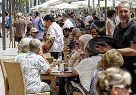 Dos camareros trabajan en la terraza de un bar.