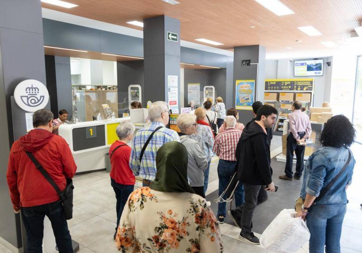 Varias personas esperan en una oficina de Correos.