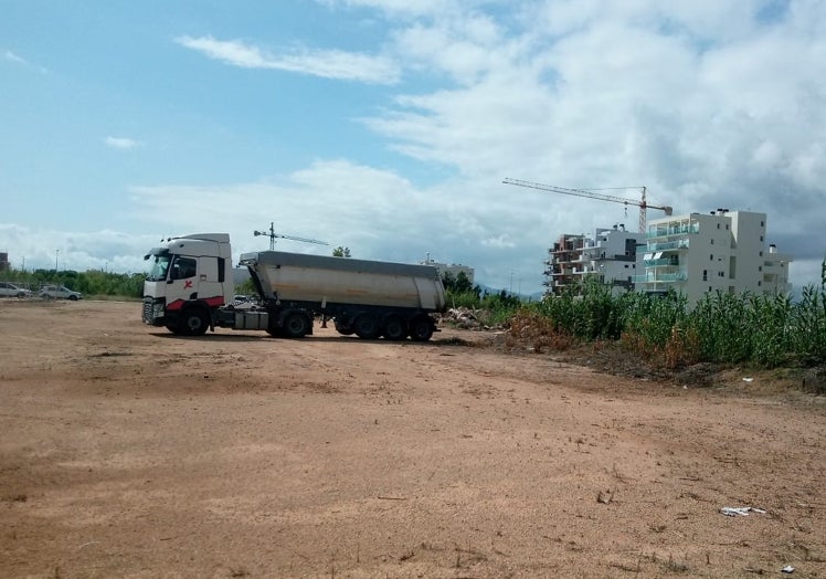 Imagen principal - Camiones y operarios trabajando en la parcela de la playa de Oliva.