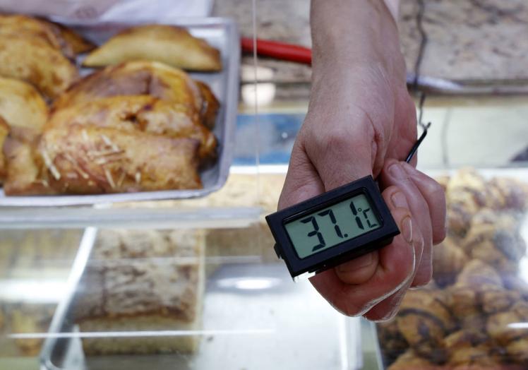 Imagen principal - Los comerciantes intentan rebajar el calor con el uso de ventiladores. 