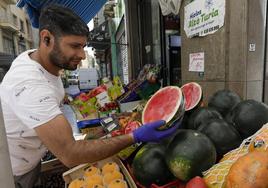 Un frutero coloca una pieza de sandía en su comercio.