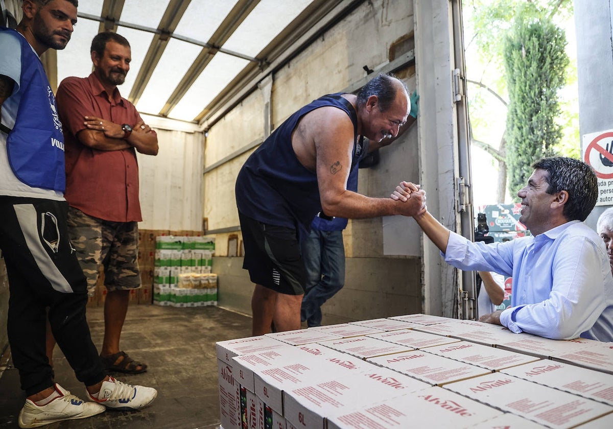 El presidente de la Generalitat, Carlos Mazón, saluda a uno de los voluntarios del almacén de la entidad ubicada en la Pobla del Vallbona.