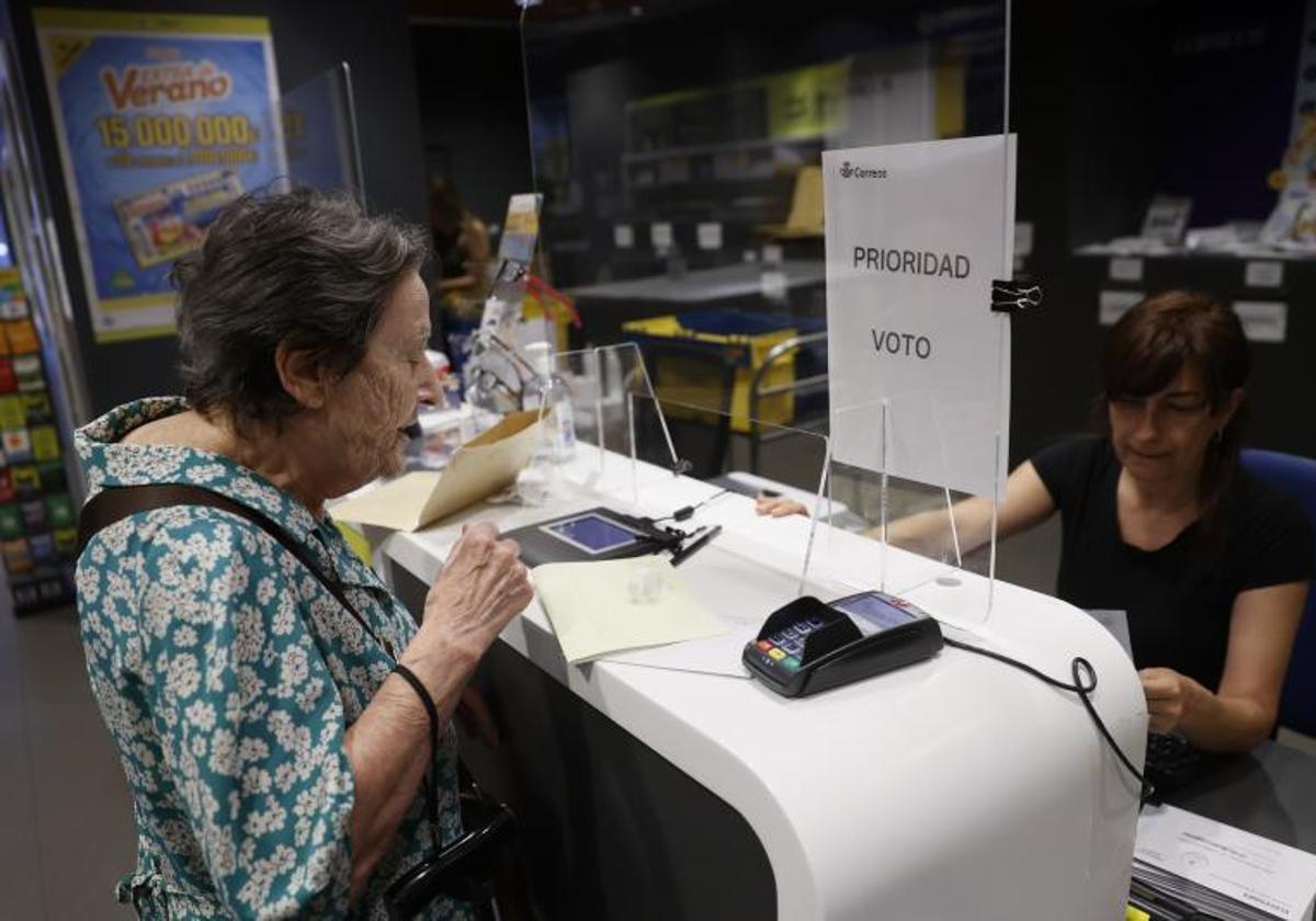 Una mujer entrega la documentación para ejercer el voto por correo en una oficina.