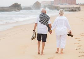 Una pareja pasea tranquilamente por la playa.