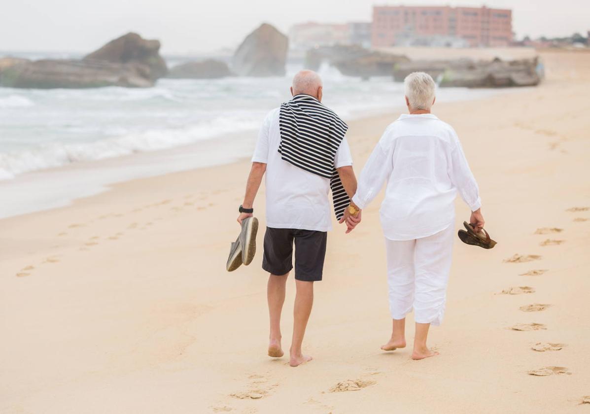 Una pareja pasea tranquilamente por la playa.