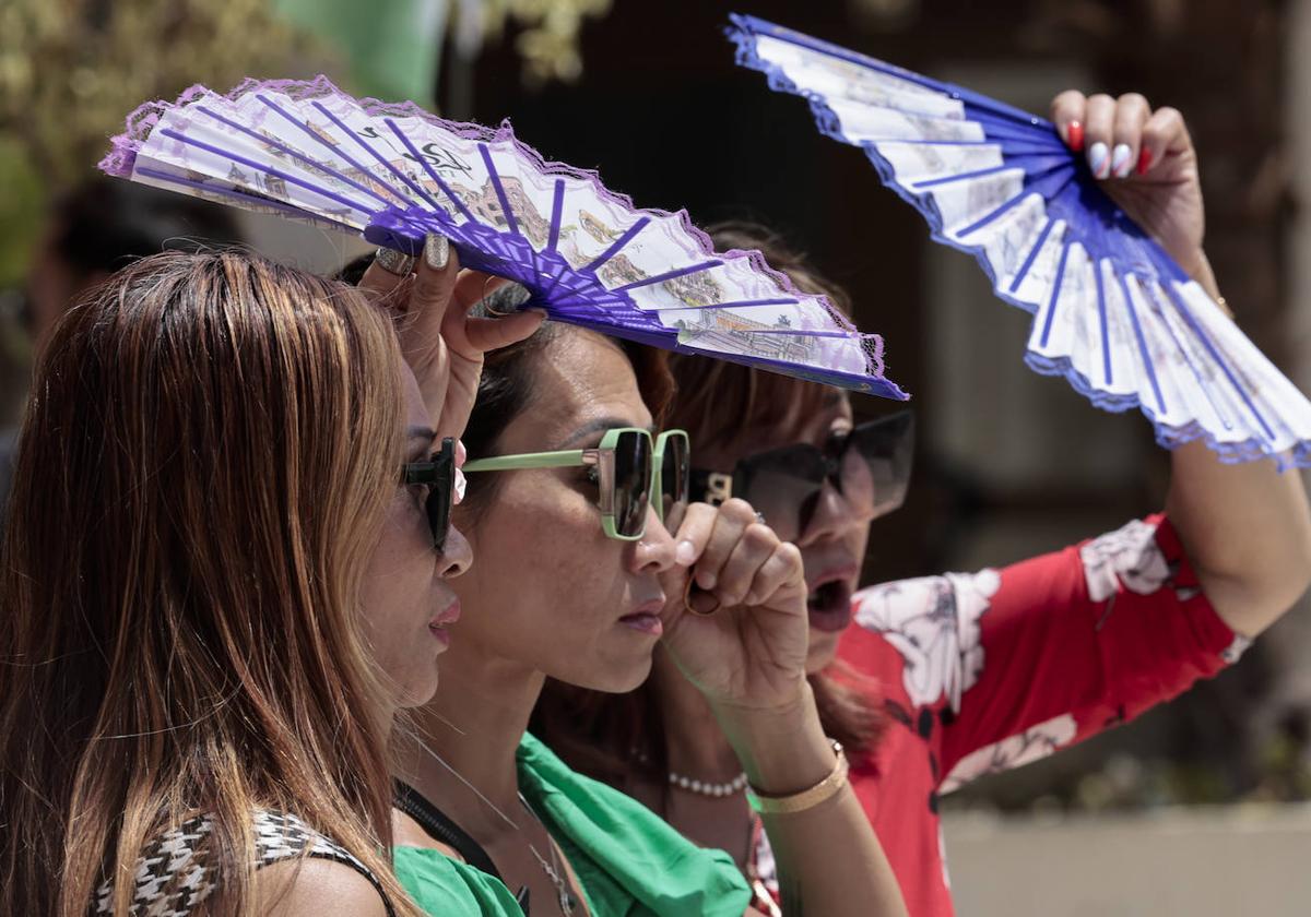 Unas turistas se protegen del calor en Valencia con abanicos.