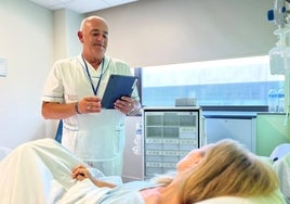 Personal sanitario hace uso de una tablet junto a una paciente.