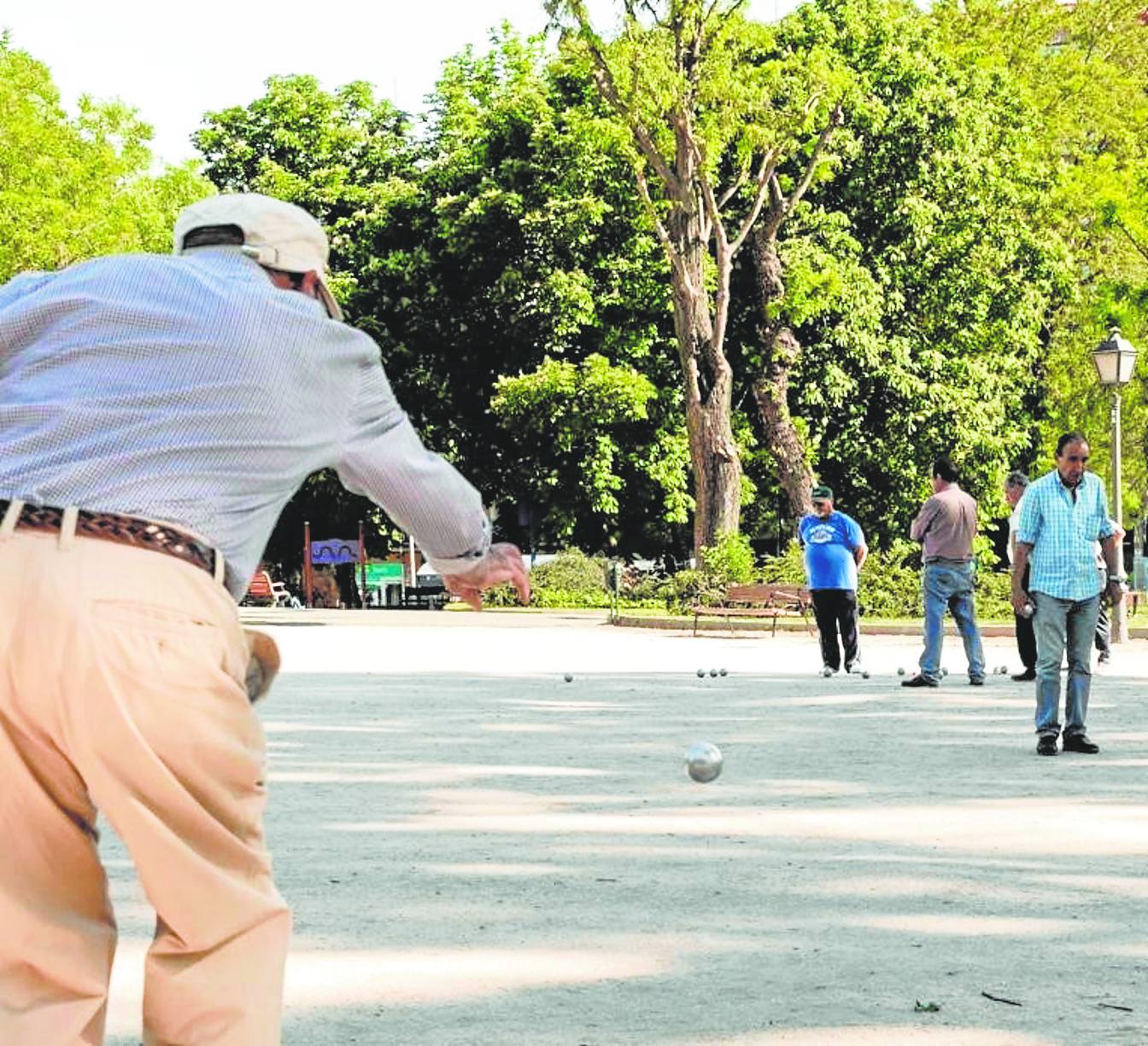 Jubilados juegan a la petanca en un parque.