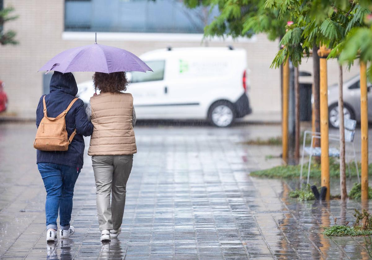 Una pareja se resguarda de la lluvia con su paraguas en Valencia