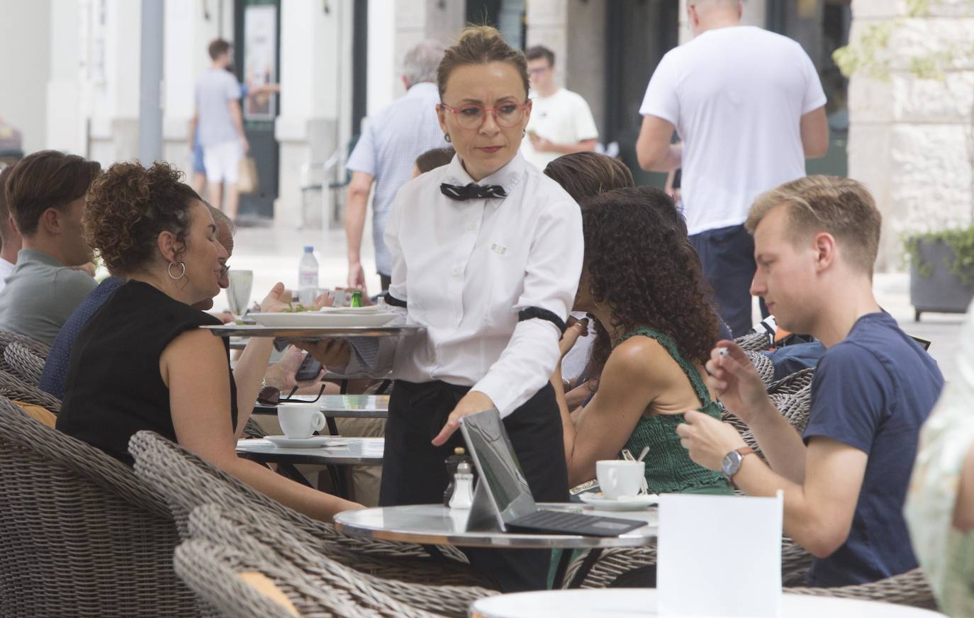 Una camarera atienda una mesa en una terraza de Valencia.