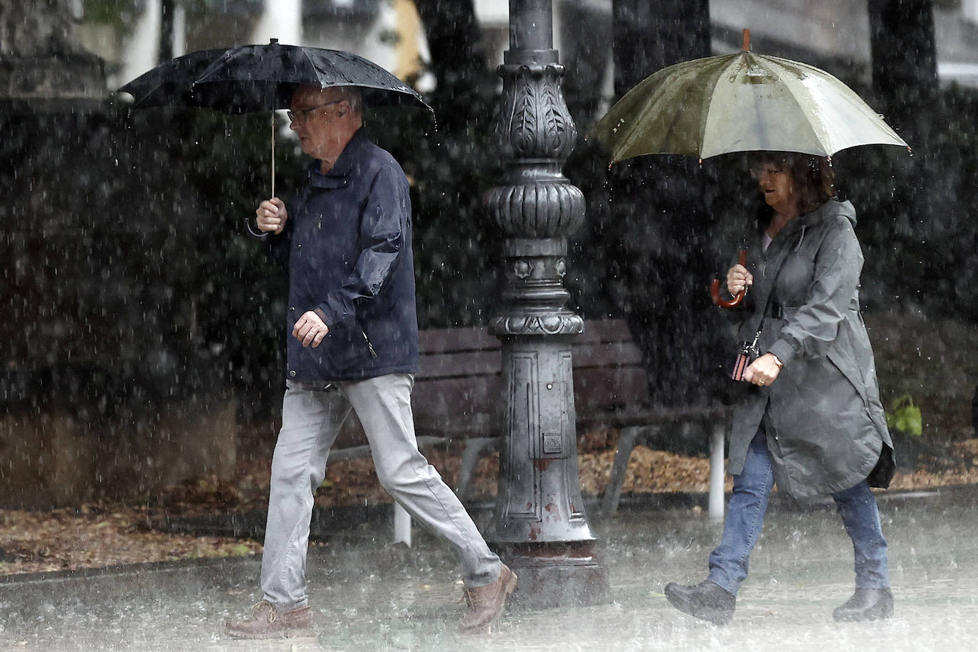 Dos personas se refugian de las fuertes lluvias en una imagen de archivo.