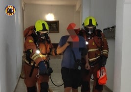 Dos bomberos auxilian a una de las víctimas del incendio de Alfafar.