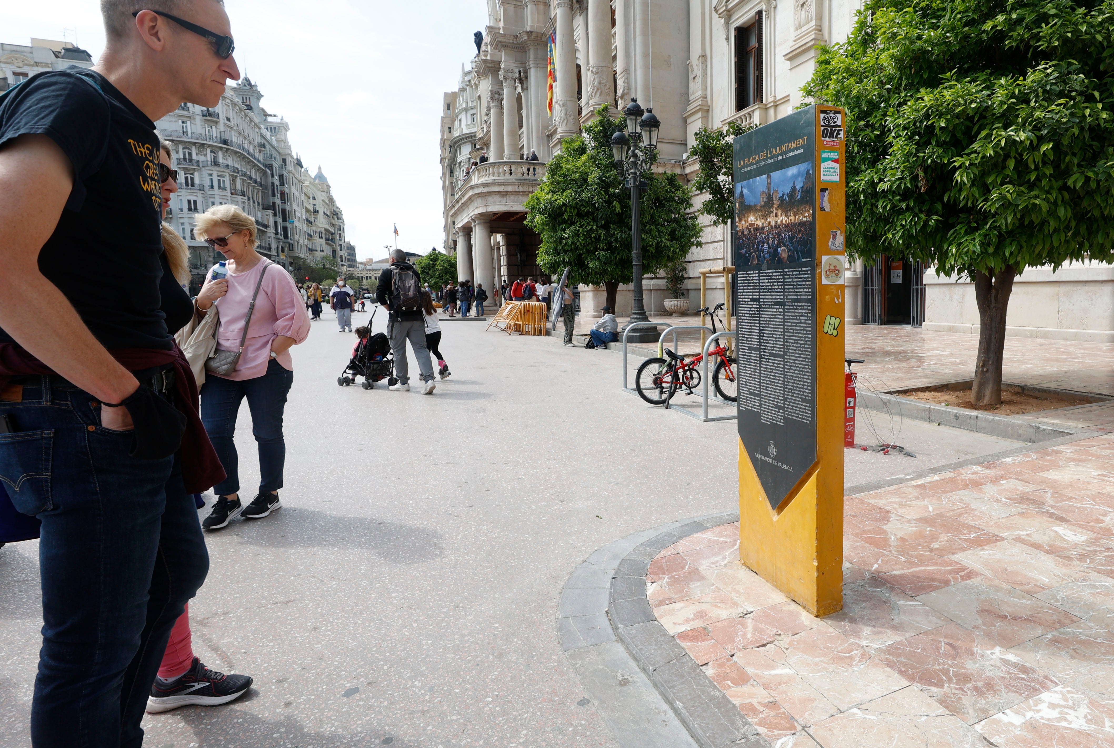 Un hombre contempla el monolito conmemorativo del 15-M junto al Ayuntamiento de Valencia.