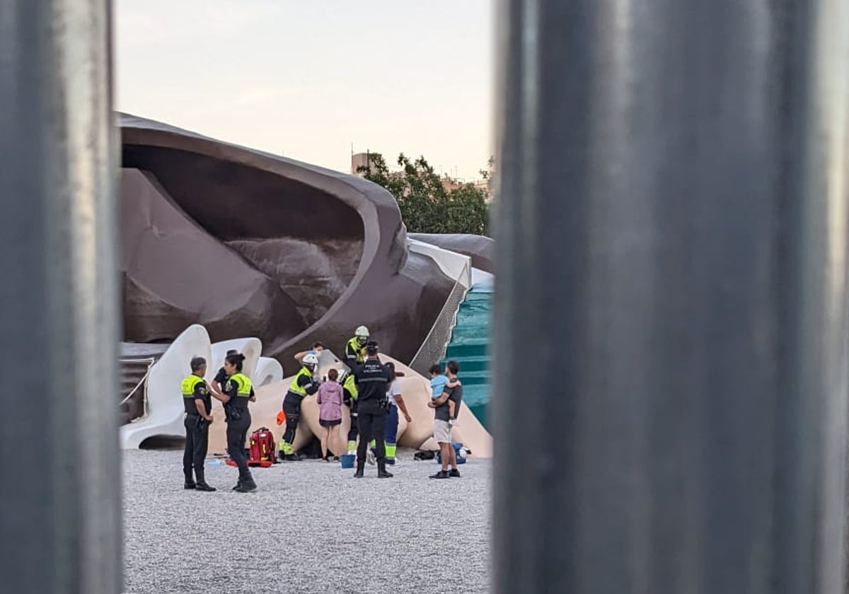 Los bomberos y policías, el domingo por la tarde, junto al menor en apuros en la mano del Gulliver.