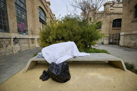 Una persona sin hogar, durmiendo en un banco de Valencia, en imagen de archivo.