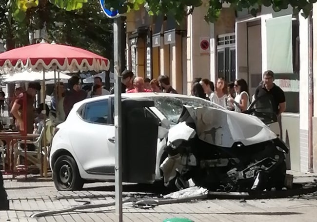 Clientes del bar y vecinos junto al coche siniestrado.