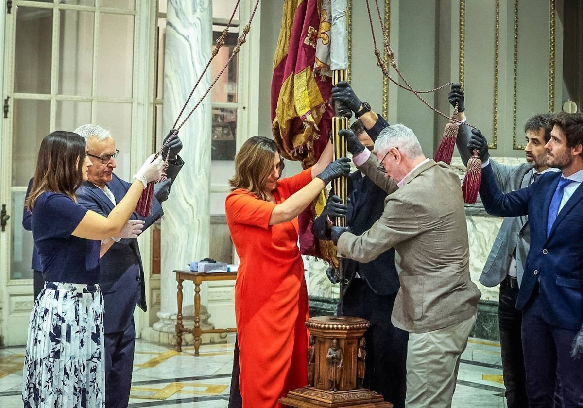 La alcaldesa de Valencia, María José Catalá, en el momento de instalar la Real Senyera en la peana del Salón de Cristal.