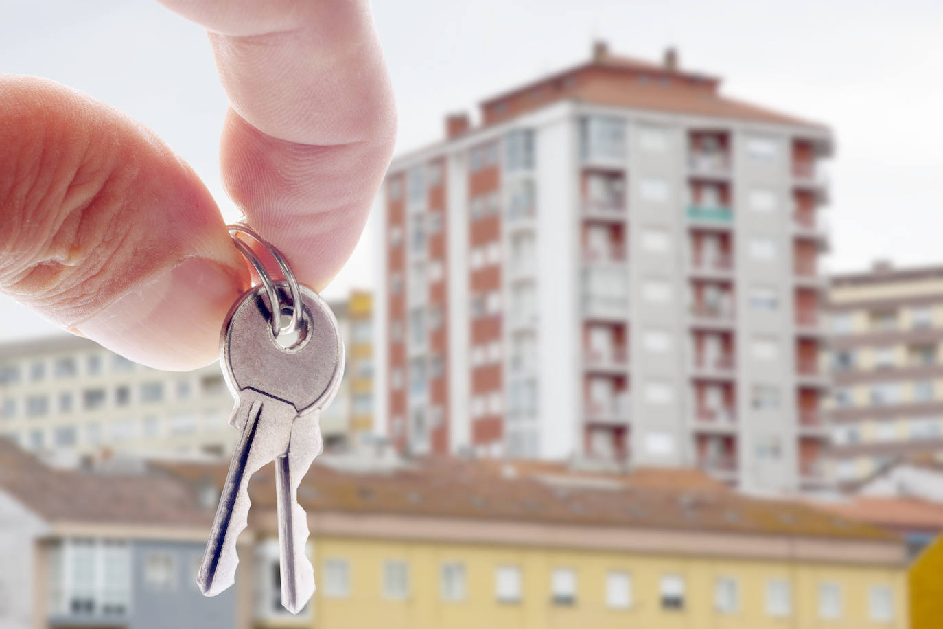 Unas llaves de una casa junto a una vivienda.