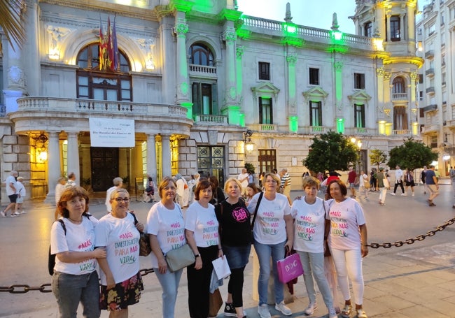 Enfermas de cáncer de mama metastásico junto a la fachada iluminada del Ayuntamiento de Valencia.