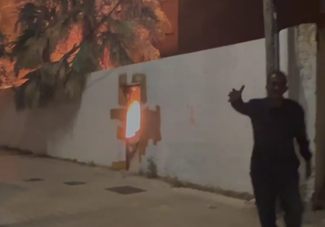 Un hombre junto a la puerta del solar en llamas antes de que llegaran los bomberos.