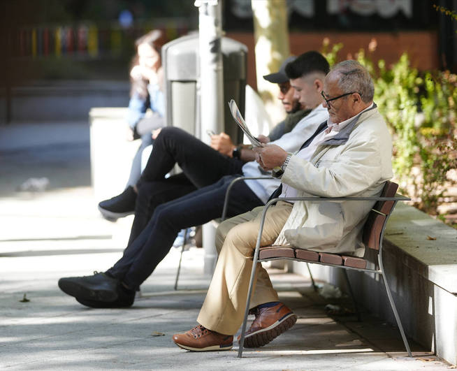 Tres hombres descansan sentados en un parque.