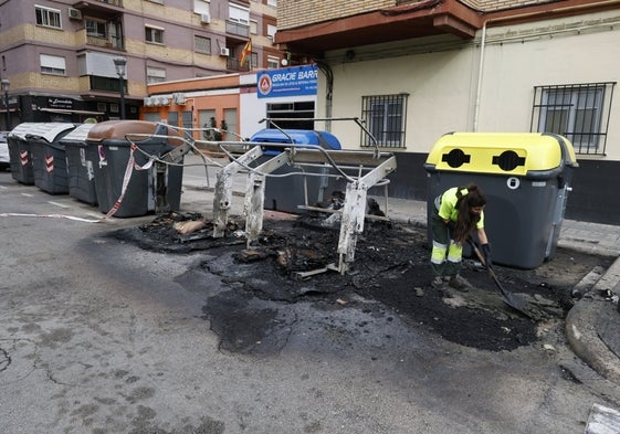 Una empleada municipal limpia la zona quemada junto a los contenedores.