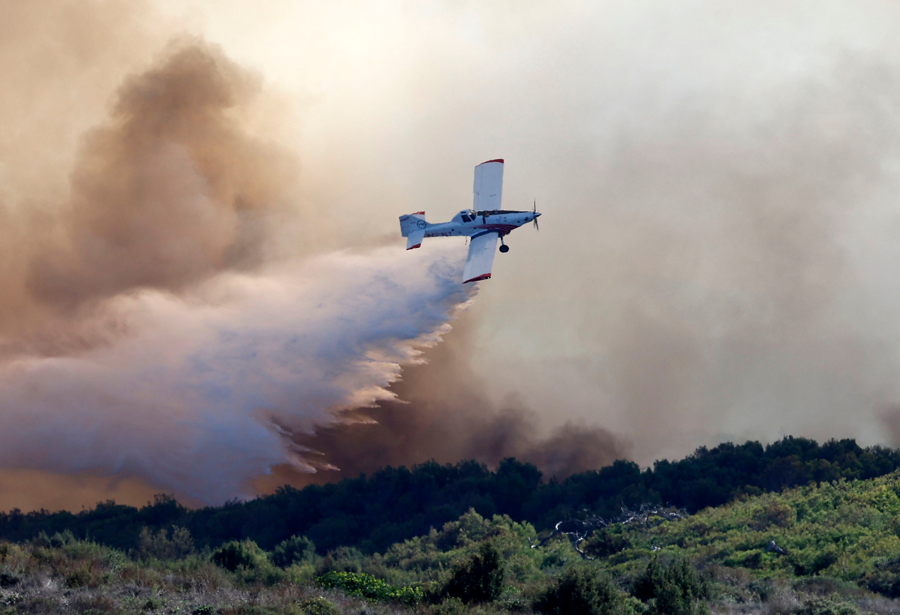 Una avioneta realiza una descarga de agua durante el incendio que afectó este sábado a El Saler.