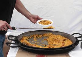 Un cocinero sirve un plato de paella.